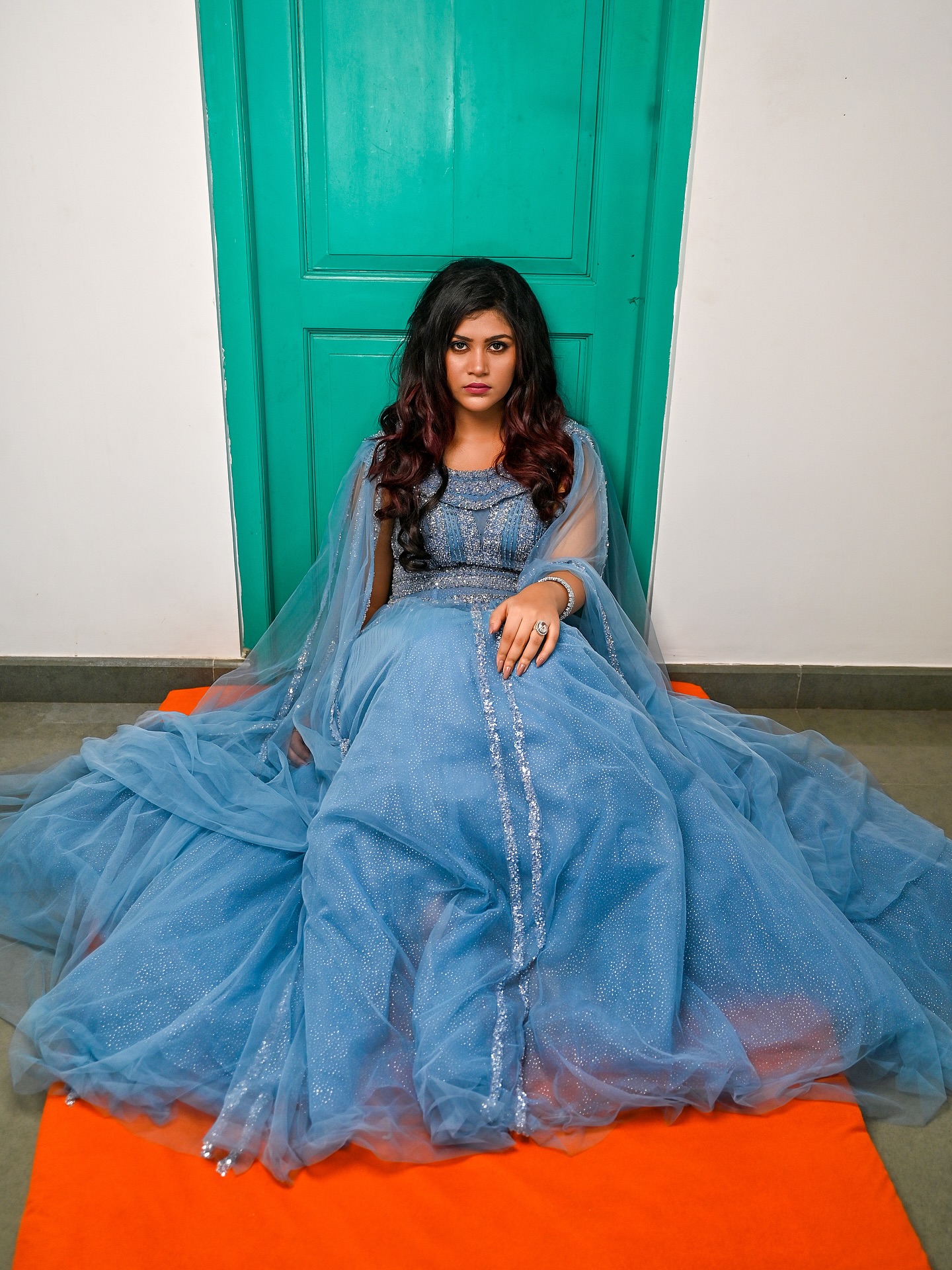 Bride-to-be in blue tulle gown against teal door