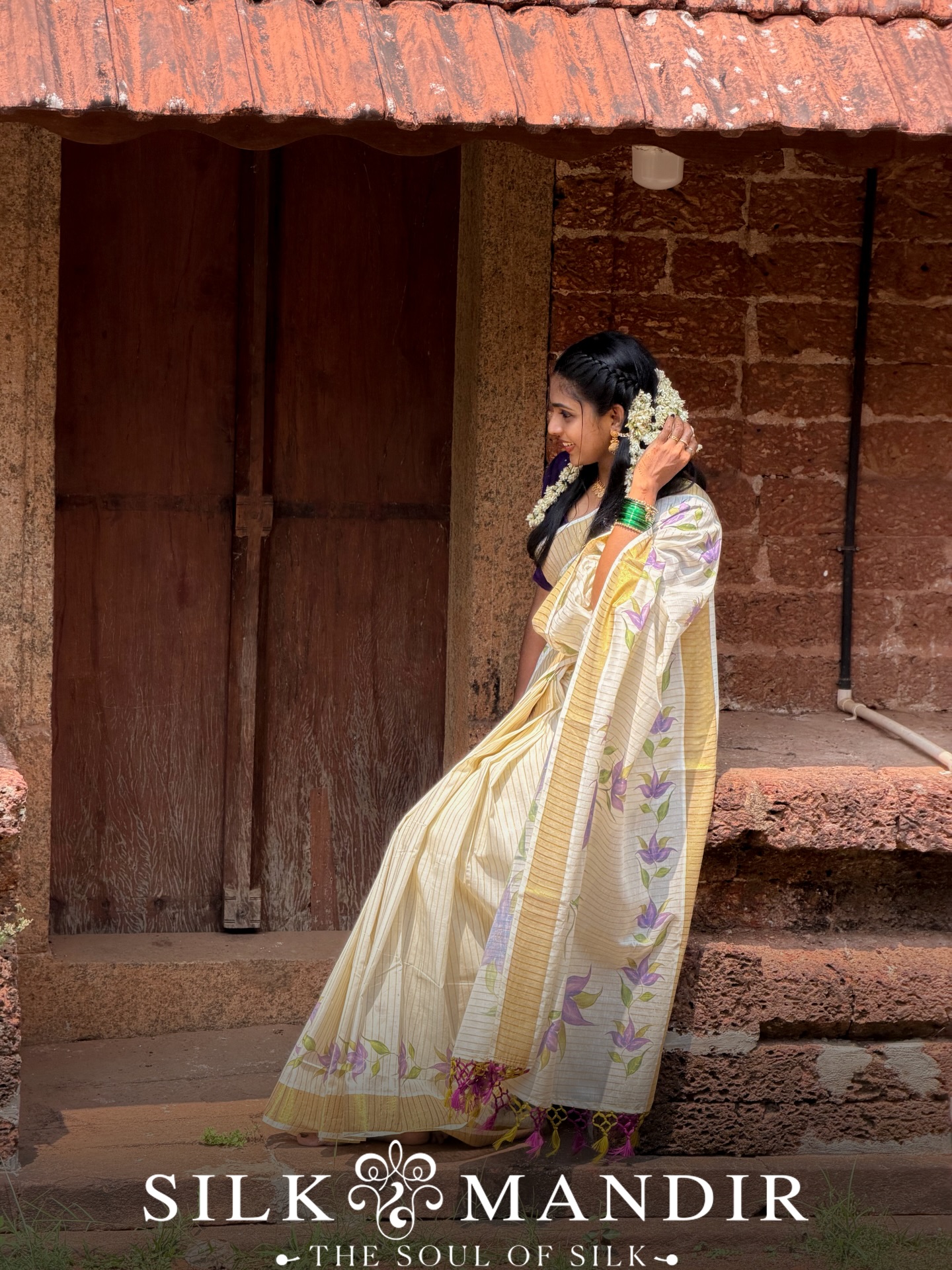 Cream Kerala kasavu saree against laterite stone wall